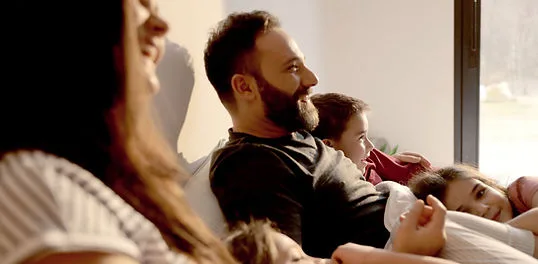 Famille regardant la télévision, grâce à nos solutions pour une tranquillité d'esprit à la maison.